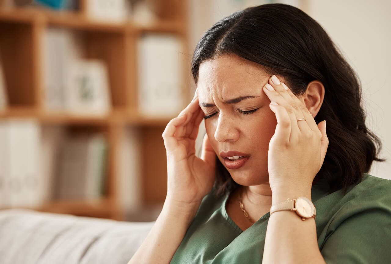 Person holding their head in pain from a recurring headache that may need chiropractic treatment.