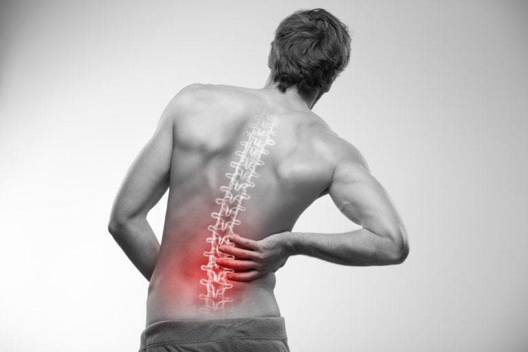 Person holding their lower back, indicating chronic lower back pain.